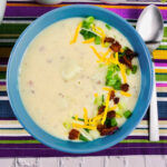 top down view of a bowl of loaded baked potato soup in a blue bowl