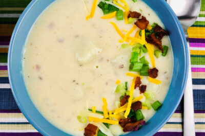 top down view of a bowl of loaded baked potato soup in a blue bowl