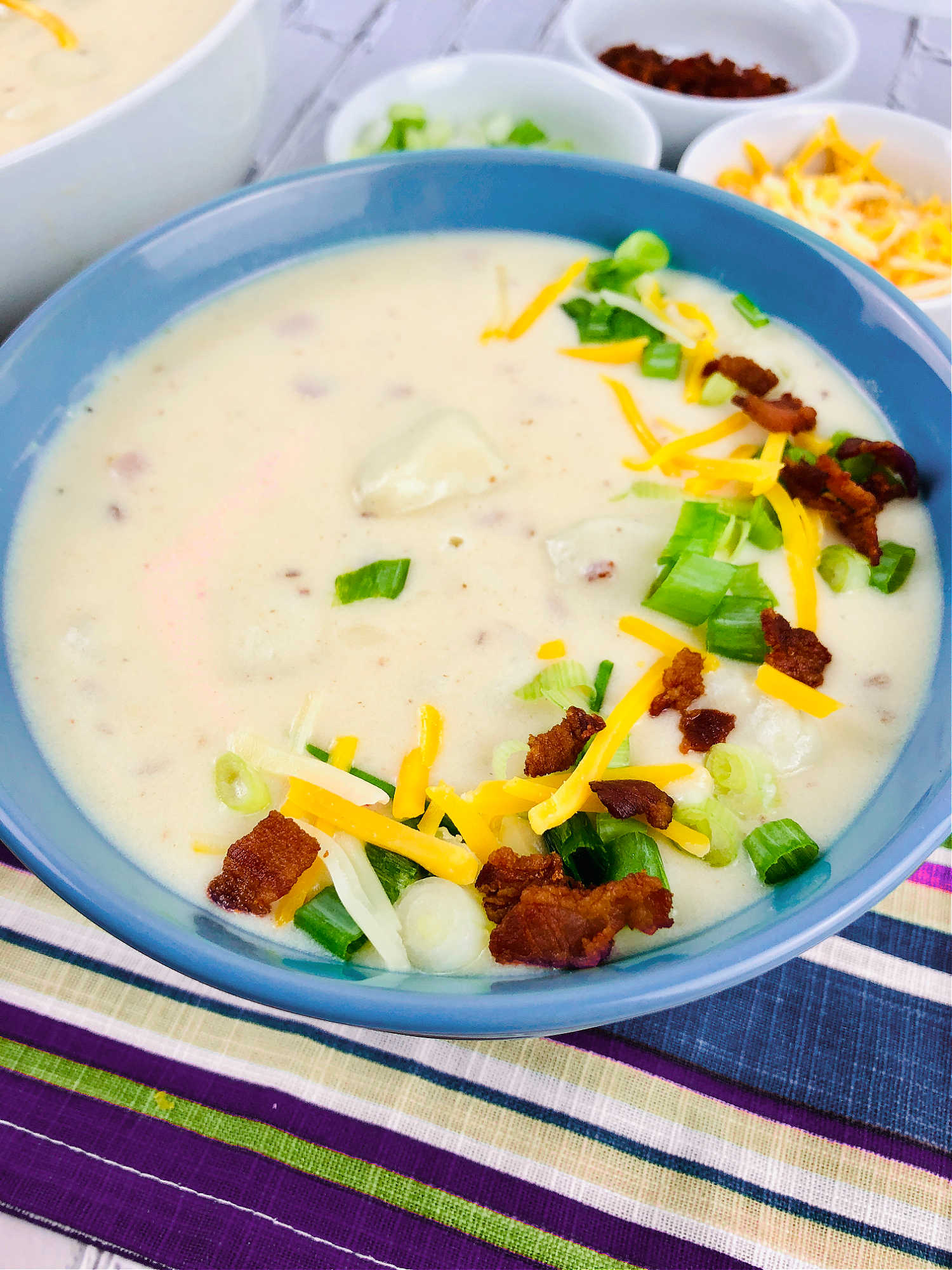 close up of a bowl of loaded baked potato soup in a blue bowl