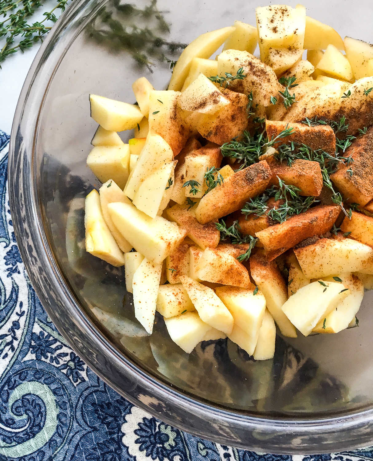 A mixing bowl of chopped apples and herbs