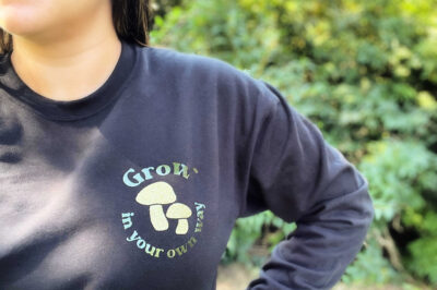 woman wearing a black sweatshirt with a Grow in Your Own Way pocket design