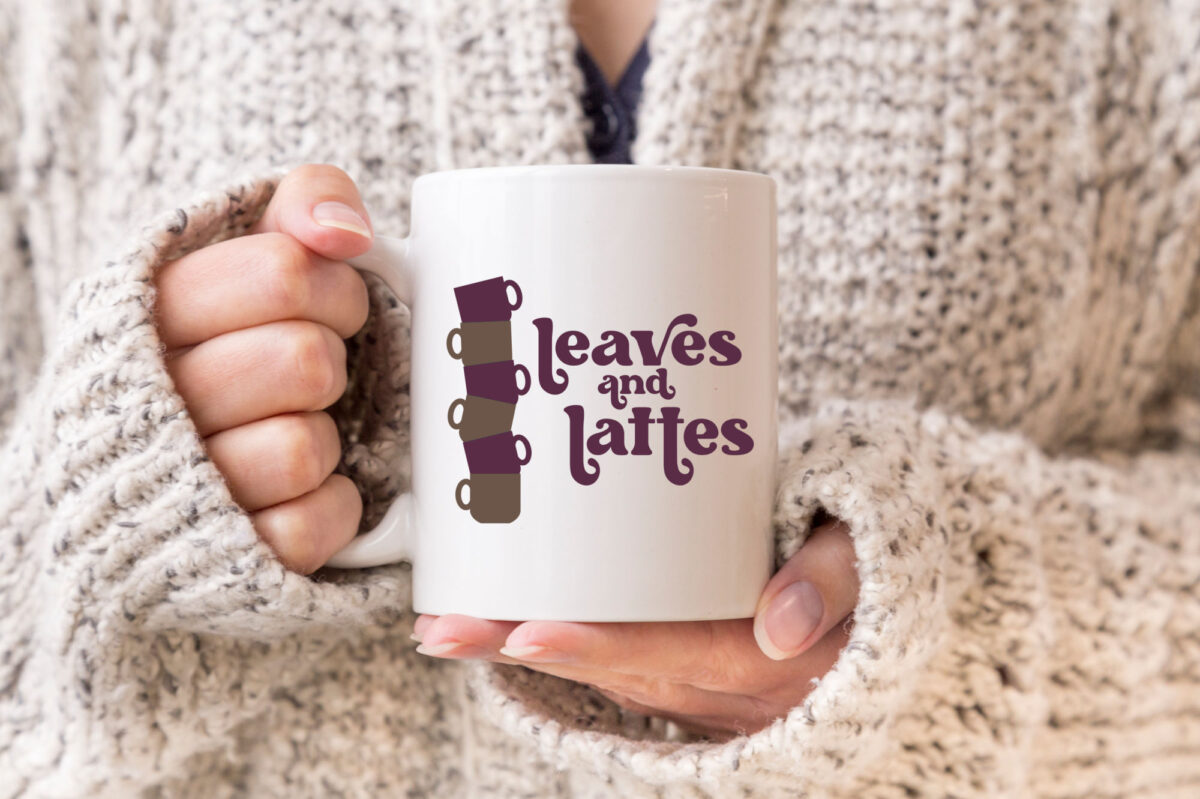 woman in a white sweater holding a leaves and lattes mug