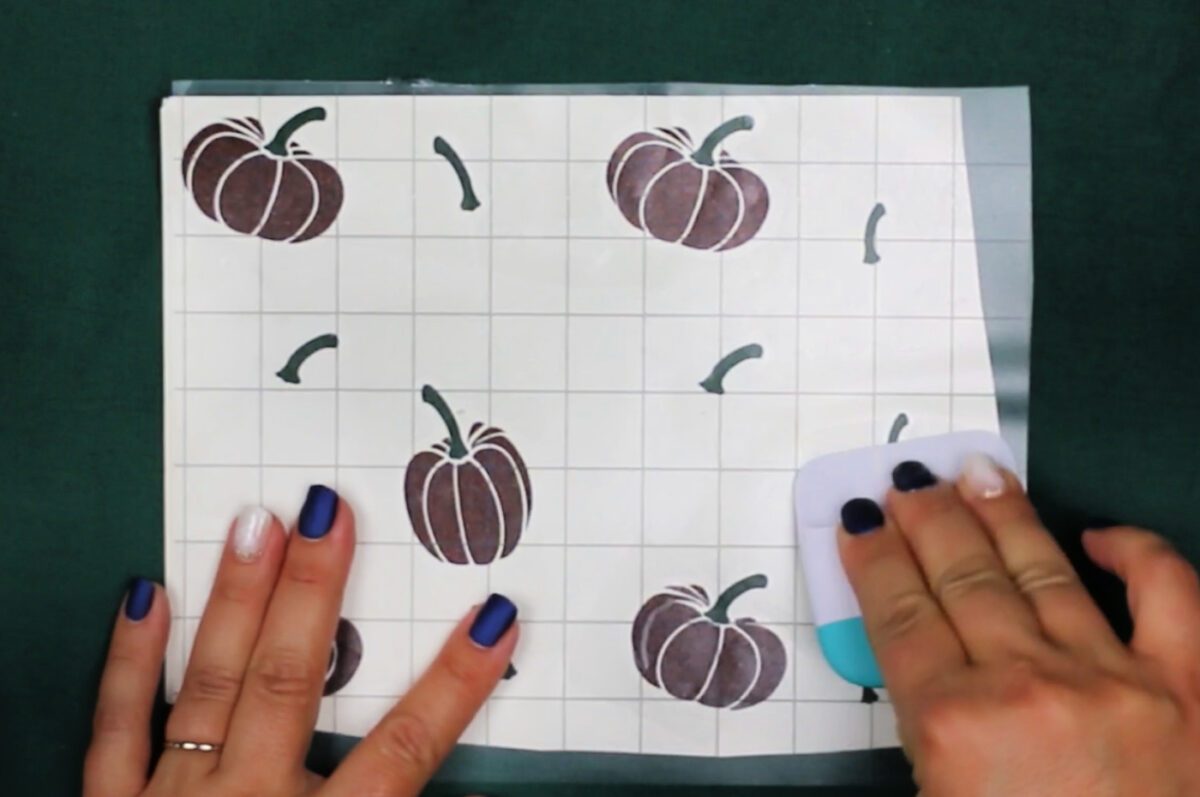 woman's hands scraping transfer tape onto weeded vinyl