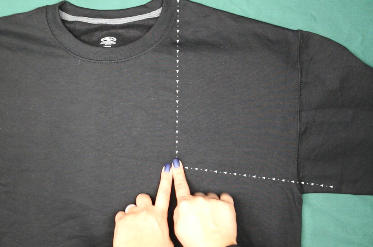 woman's hands indicating where a pocket design would go on a black shirt