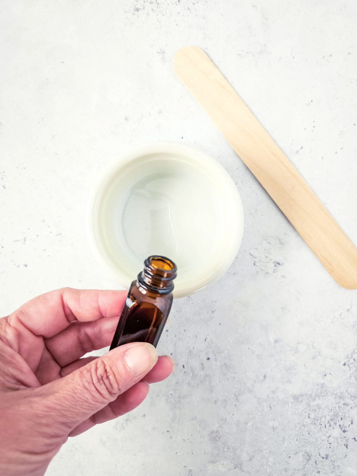 woman's hand pouring fragrance oil into epsom salt