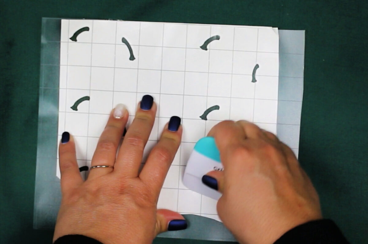 woman's hands scraping transfer tape onto weeded vinyl