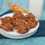 side view of pumpkin no bakes on a white plate near a bottle of milk