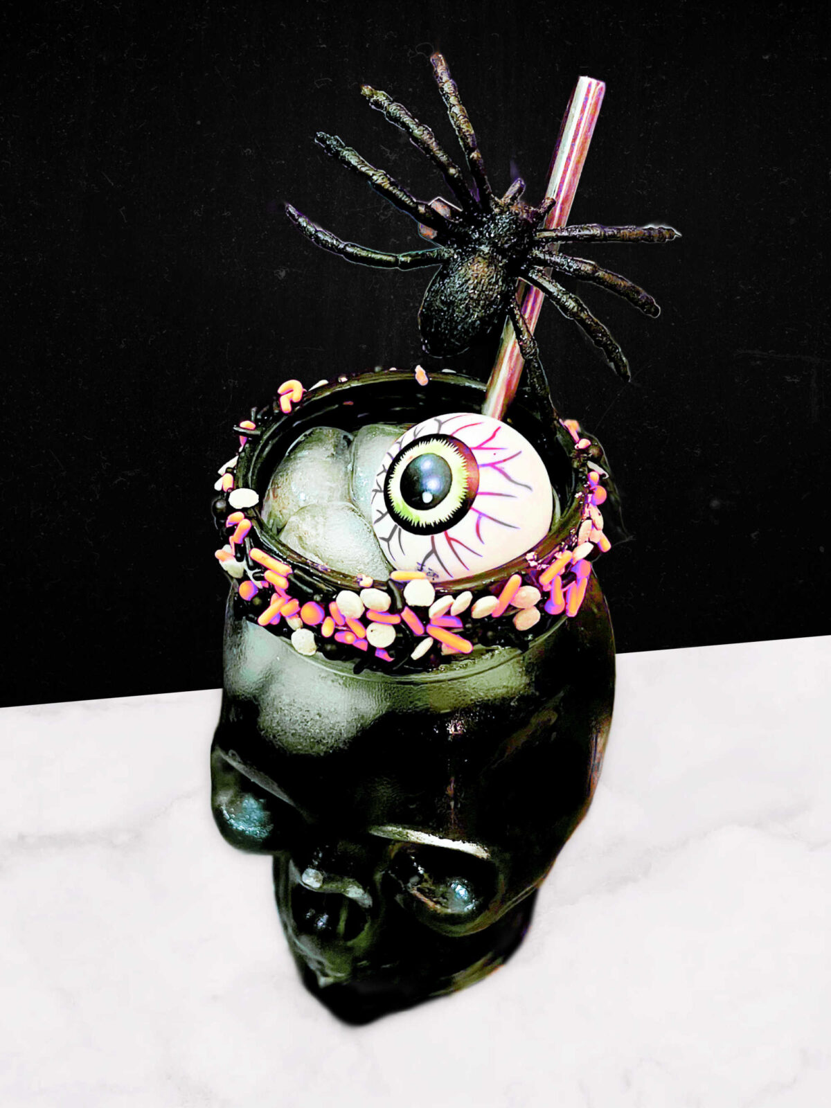 black margarita cocktail in a skull shaped glass rimmed with Halloween sprinkles