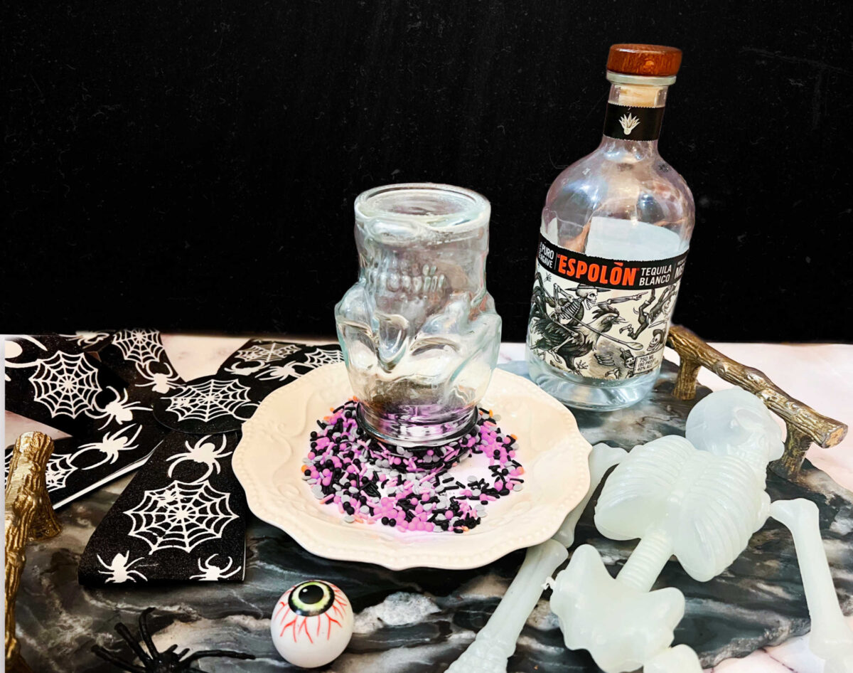 skull shaped glass upside down in a plate of halloween sprinkles