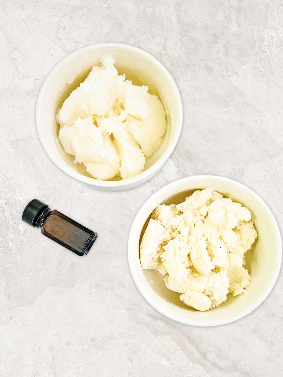 a bowl of shea butter, a bowl of solid coconut oil, and a vial of essential oil