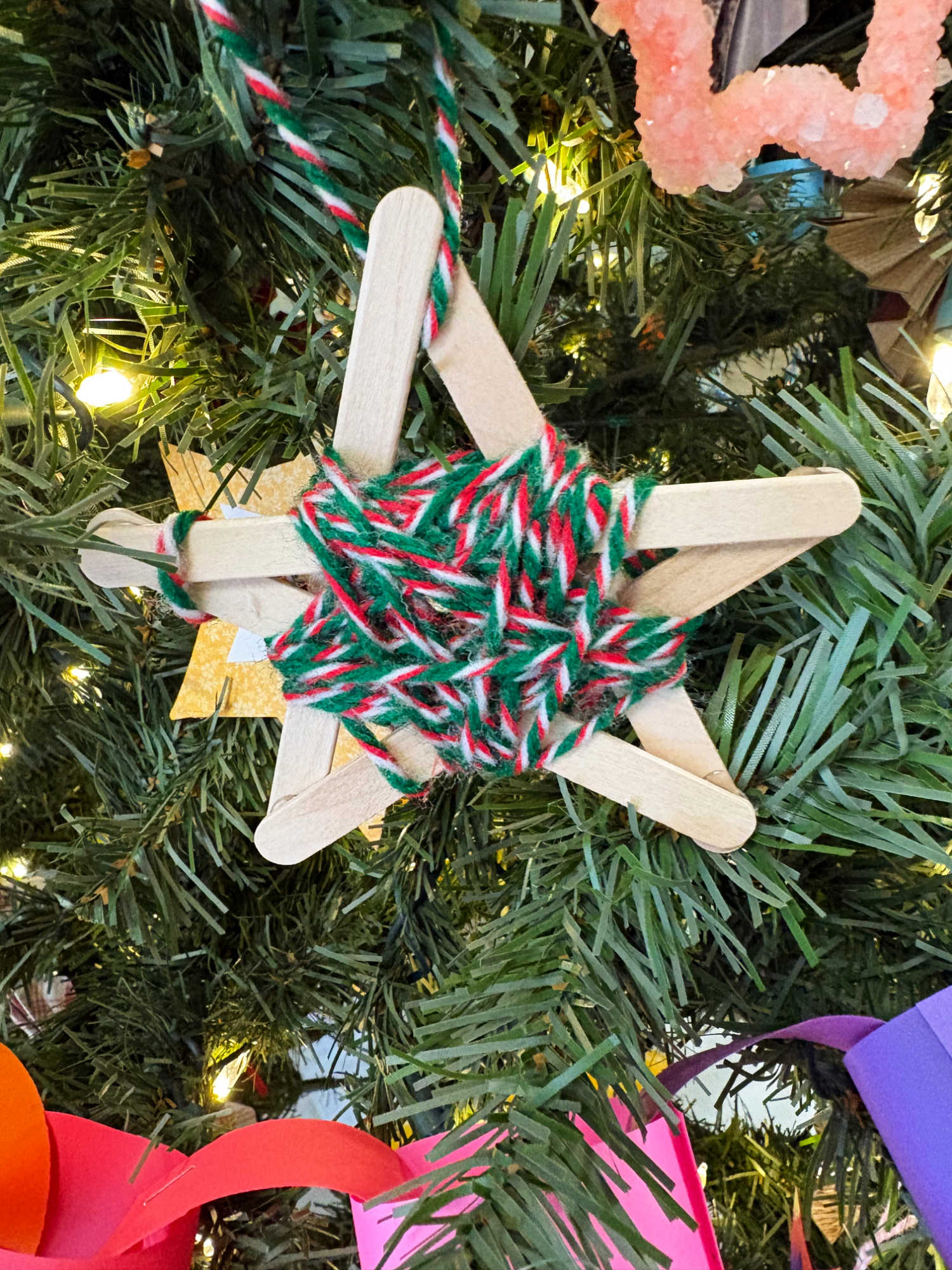 christmas ornament made from popsicle sticks and yarn on a tree