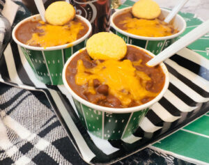 3 bowls of chili topped with cheese and a mini cornbread muffin