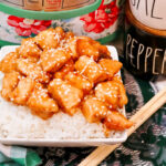 a serving of firecracker chicken in a bowl near chopsticks