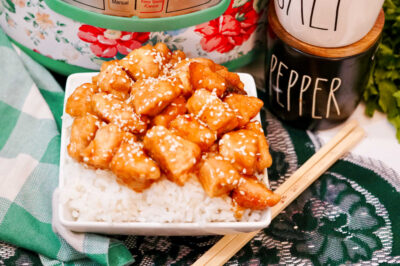 a serving of firecracker chicken in a bowl near chopsticks